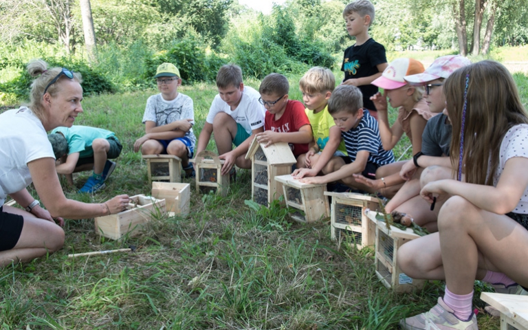 Dzieci z półkolonii podczas budowania domków dla owadów