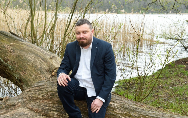 dr Sławomir Kasiński siedzi nad jeziorem