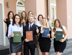 absolwenci  stoją z dyplomami
